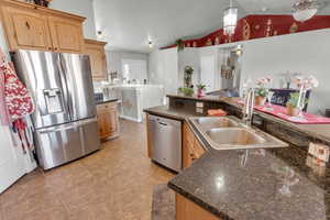 Kitchen with sink, vaulted ceiling, hanging light fixtures, light tile patterned floors, and stainless steel appliances