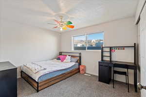 Bedroom featuring ceiling fan, carpet, and a textured ceiling