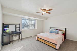 Bedroom featuring ceiling fan, carpet floors, and a textured ceiling