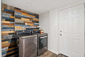 Laundry area with dark hardwood / wood-style floors and washing machine and clothes dryer