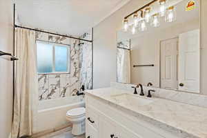 Full bathroom with wood-type flooring, vanity, shower / tub combo, toilet, and a textured ceiling