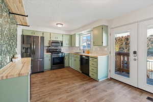 Kitchen featuring appliances with stainless steel finishes, sink, green cabinets, and light hardwood / wood-style flooring