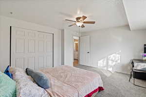 Bedroom featuring ceiling fan, a closet, light carpet, and a textured ceiling