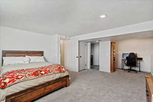 Bedroom featuring light carpet and a textured ceiling