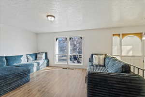 Living room with light hardwood / wood-style floors and a textured ceiling