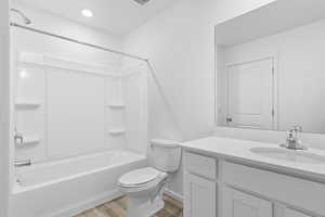 Full bathroom featuring vanity, hardwood / wood-style floors, shower / bathtub combination, and toilet