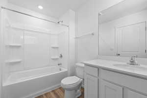 Full bathroom with vanity, hardwood / wood-style floors, bathing tub / shower combination, and toilet