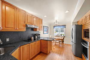 Kitchen with pendant lighting, sink, crown molding, appliances with stainless steel finishes, and kitchen peninsula