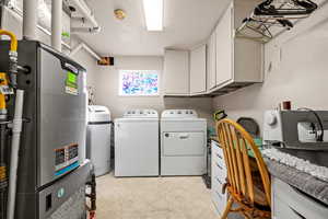 Laundry room with cabinets, separate washer and dryer, and a textured ceiling