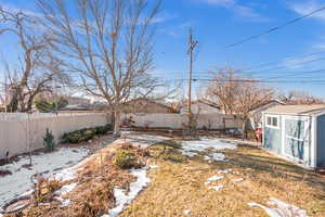 Yard covered in snow featuring a shed