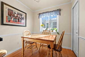 Dining space with ornamental molding and hardwood / wood-style floors