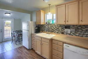 Kitchen with light brown cabinetry, decorative light fixtures, and decorative backsplash