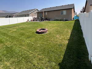 View of yard during the summer featuring an outdoor fire pit