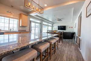 Kitchen featuring sink, stone counters, a tray ceiling, dark hardwood / wood-style flooring, and decorative light fixtures
