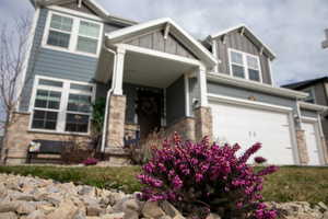 Craftsman inspired home featuring an attached garage, stone siding, and board and batten siding