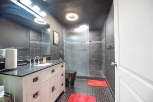 Bathroom with vanity, tiled shower, and a textured ceiling