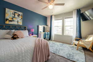 Carpeted bedroom featuring ceiling fan and a textured ceiling