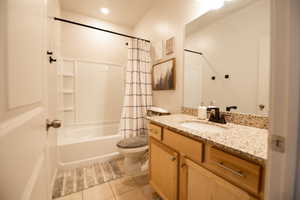 Full bathroom featuring toilet, vanity, shower / bathtub combination with curtain, and tile patterned flooring