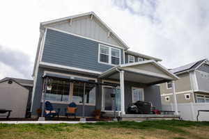 Rear view of house with a lawn, fence, board and batten siding, and a patio