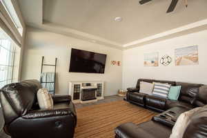 Living room featuring a tray ceiling, a textured ceiling, ceiling fan, and hardwood / wood-style flooring