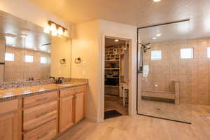 Bathroom featuring vanity, a textured ceiling, wood-type flooring, and tiled shower