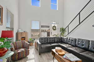 Living room with light hardwood / wood-style floors and a high ceiling