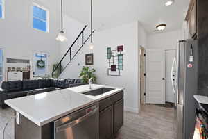 Kitchen with dark brown cabinetry, sink, decorative light fixtures, a center island with sink, and appliances with stainless steel finishes