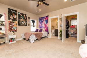 Carpeted bedroom featuring multiple windows, ensuite bath, ceiling fan, and a spacious closet