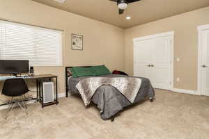 Carpeted bedroom featuring ceiling fan and a closet