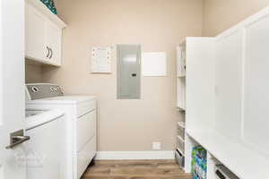 Washroom with independent washer and dryer, cabinets, electric panel, and light wood-type flooring