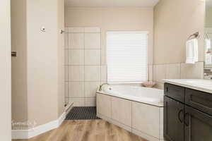 Bathroom with vanity, a bathtub, hardwood / wood-style flooring, and tile walls