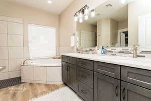 Bathroom featuring wood-type flooring, a tub, tile walls, and vanity