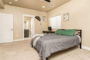 Bedroom with ceiling fan, light colored carpet, and ensuite bathroom