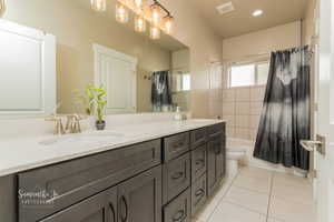 Full bathroom with vanity, toilet, tile patterned flooring, and shower / bath combo with shower curtain