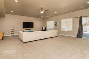 Carpeted living room featuring a textured ceiling and ceiling fan