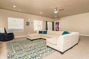 Living room featuring ceiling fan, carpet flooring, and a textured ceiling