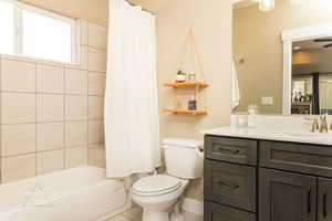 Full bathroom with vanity, shower / bath combination with curtain, and toilet