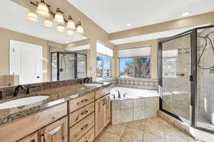 Bathroom featuring vanity, tile patterned flooring, separate shower and tub.