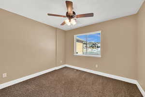 Carpeted spare room featuring ceiling fan