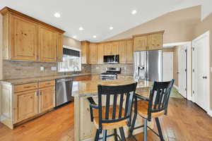 Kitchen featuring lofted ceiling, sink, stainless steel appliances, a center island, and granite counter tops