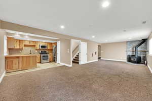 Living room in basement with light colored carpet, sink, and a wood stove