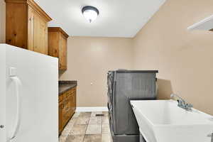 Clothes washing area with cabinets, washer / dryer, sink, and a textured ceiling