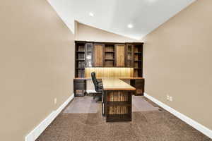 Office with lofted ceiling and dark carpet