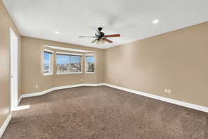 Primary bedroom with ceiling fan and carpet flooring