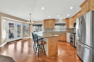 Kitchen featuring stainless steel appliances, a center island, granite counter tops, decorative backsplash, and decorative light fixtures