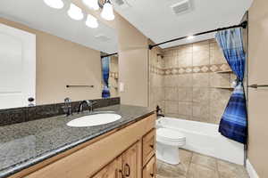 Full bathroom with tile patterned floors, toilet, a textured ceiling, vanity, and shower / bath combo