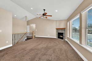 Living room with lofted ceiling, a fireplace, ceiling fan, and carpet flooring