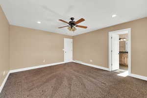 Primary bedroom featuring ceiling fan, connected bathroom, and carpet flooring