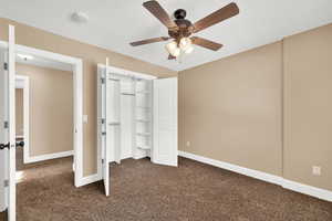 Bedroom featuring dark colored carpet, ceiling fan, and a closet