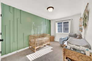 Carpeted bedroom featuring a crib